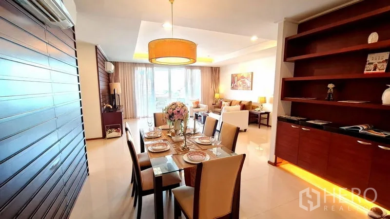 Apartment for rent in Khlong Toei, Bangkok - Six-seat dining table beside wood feature wall and shelving facing the balcony.
