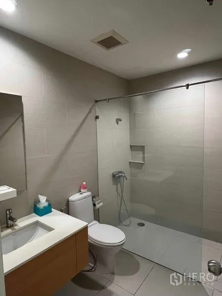 Condominium for rent in Ratchathewi, Bangkok - Modern bathroom with glass walk-in shower, toilet, and vanity.