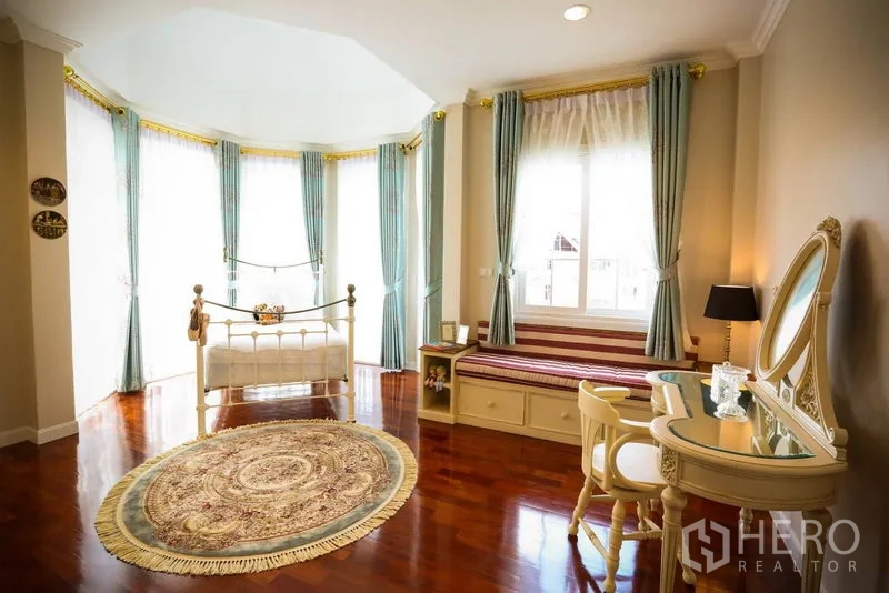 บ้าน ให้เช่าในBang Na, Bangkok - ห้องนอนมุมกระจกบานโค้ง เตียงเหล็กคลาสสิก ม้านั่งบิวท์อิน และพรมลายสวย