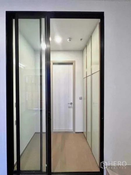公寓 出售 - 推拉玻璃门后的更衣区，带嵌入式衣柜与木地板。