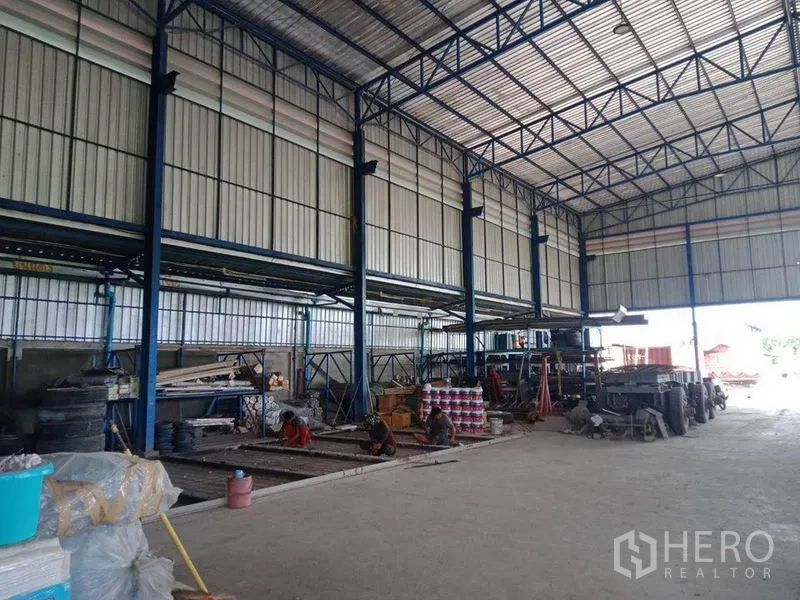 Warehouse for sale in Lam Luk Ka, Pathum Thani - Spacious steel-frame warehouse interior with high roof, storage racks and wide loading door.
