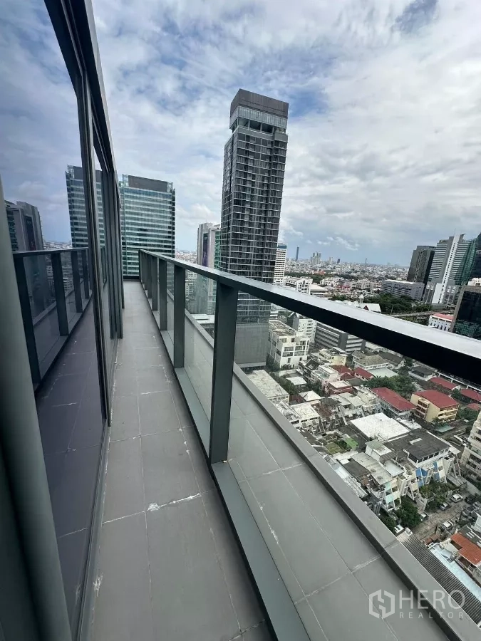 Condominium for rent in Bang Rak, Bangkok - Long balcony with glass railing overlooking the Sathorn skyline and cityscape.