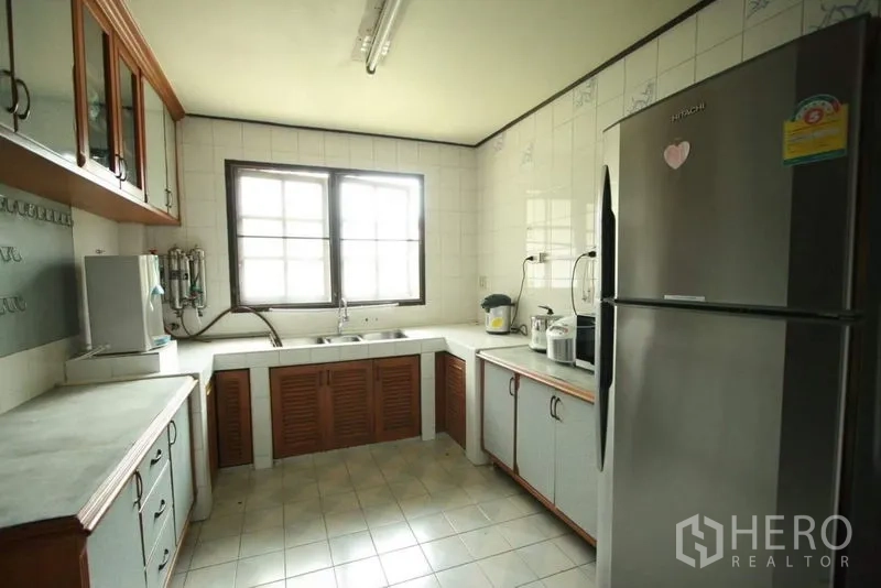 独立式住宅 出租在Bang Phli, Samut Prakan - 实用封闭式厨房，瓷砖墙面，充足台面与木柜，配不锈钢冰箱。
