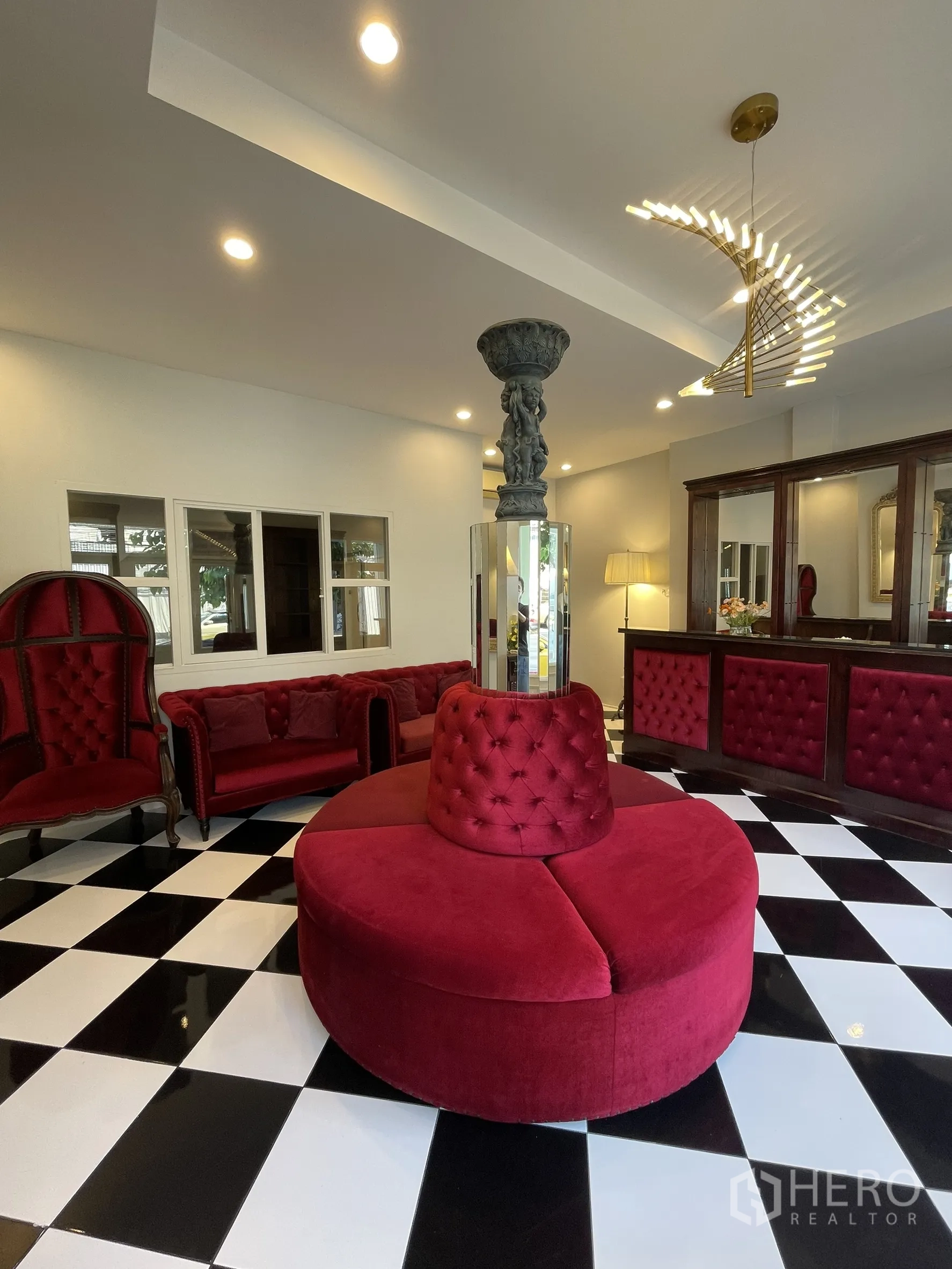 店屋 for rent in Bang Kapi, Bangkok - 优雅前厅，黑白棋盘地砖，红色天鹅绒沙发，装饰立柱与现代吊灯。