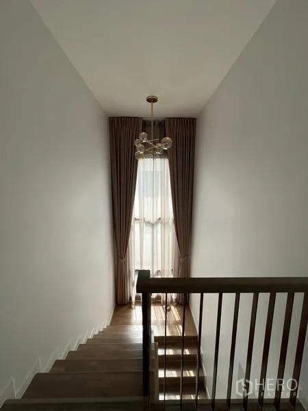 Detached House for rent in Bang Kapi, Bangkok - Staircase with high ceiling, pendant light and tall curtained window.