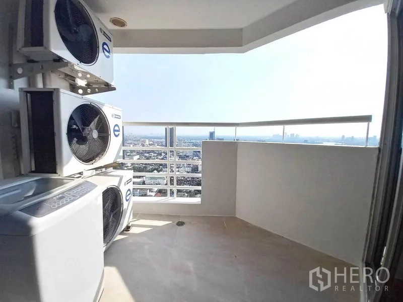 Condominium for rent in Khlong Toei, Bangkok - Covered balcony with city skyline view and outdoor laundry with AC units.