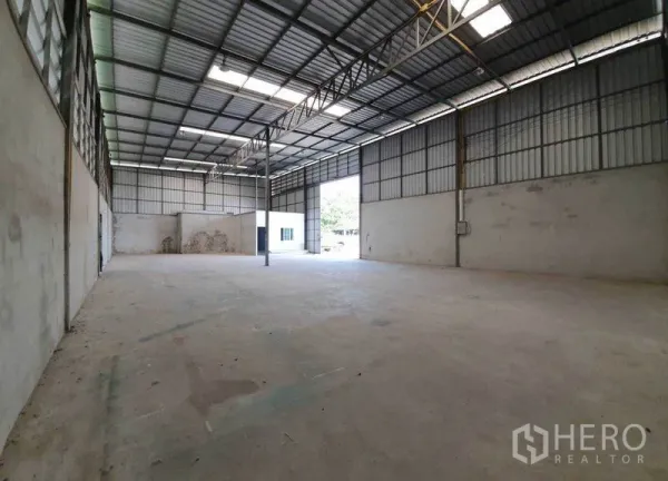 货栈 出租在Pathum Thani - 宽敞开放库区，带天窗、中心立柱和可供卡车进出的卷帘门。
