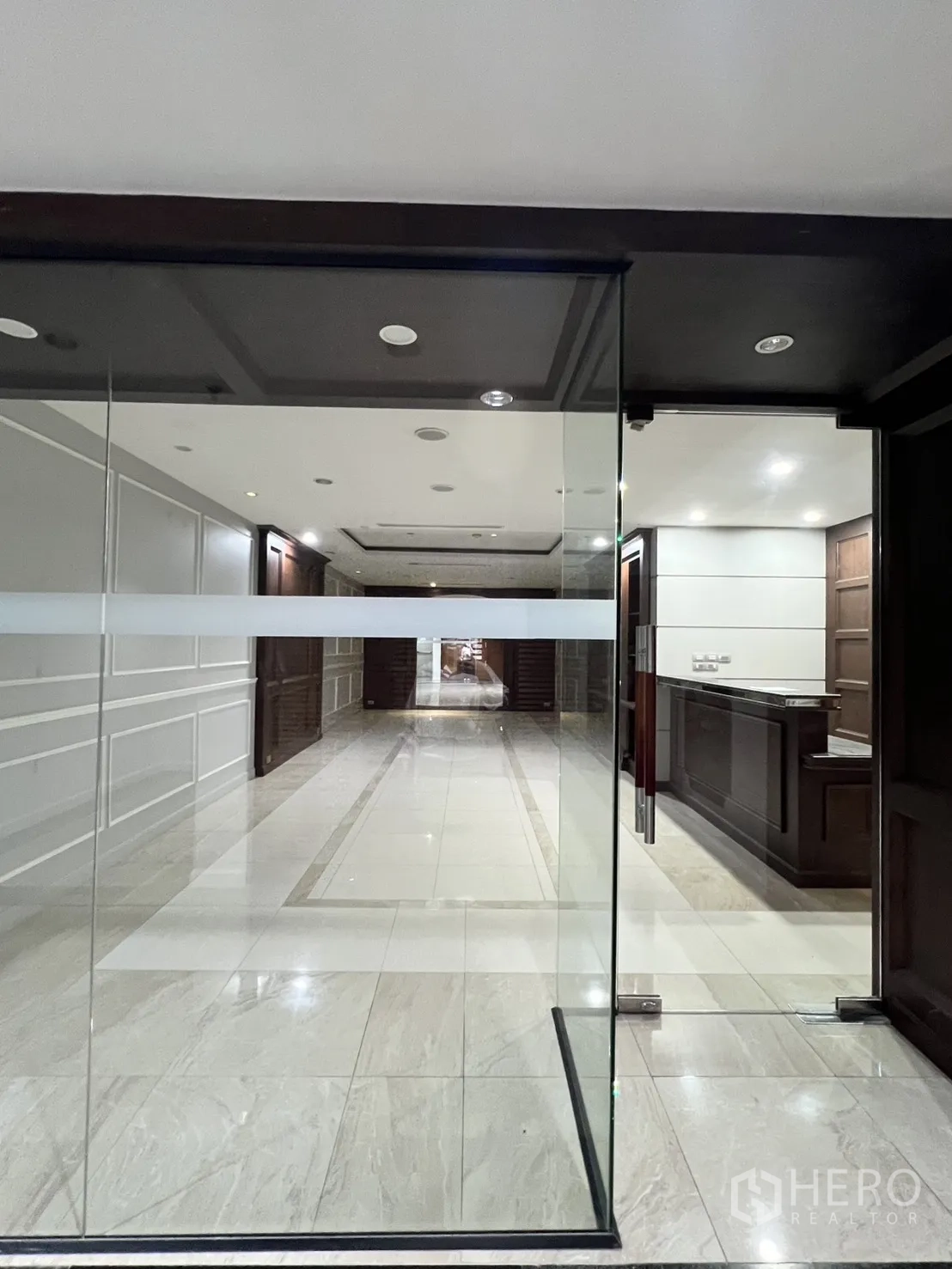 Office Space for rent in Watthana, Bangkok - View through glass doors to a bright lobby and reception counter.