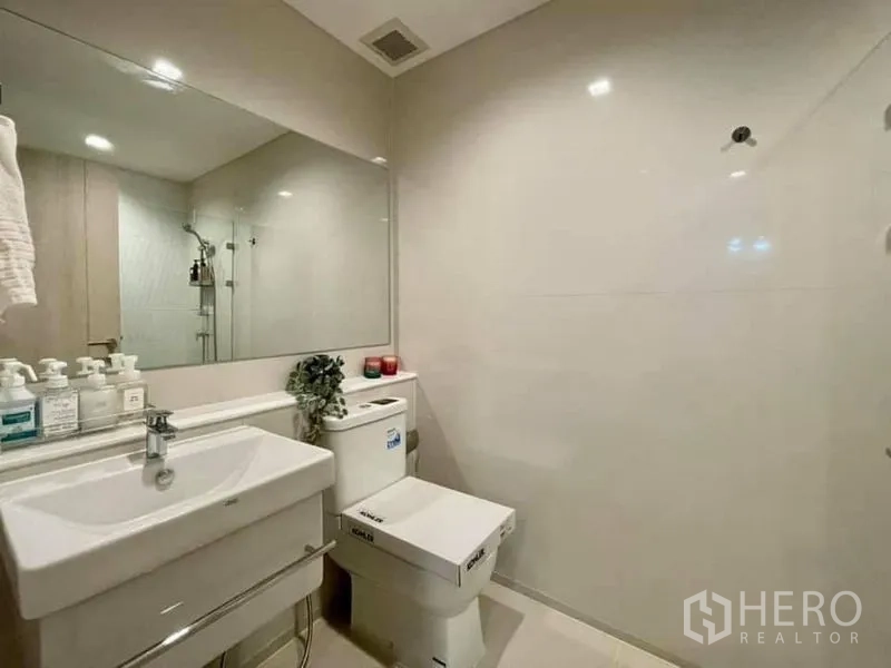 公寓 出租在Pathum Wan, Bangkok - 明亮卫生间，壁挂式洗手台、大镜面与科勒坐便器，配色简洁。