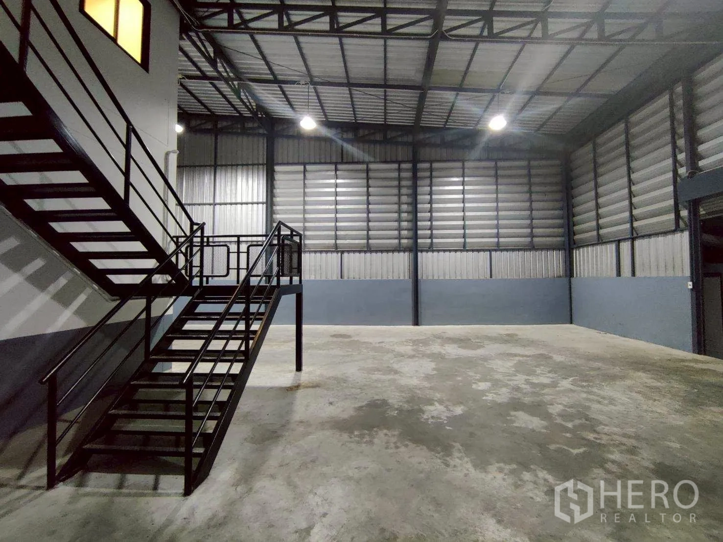 Warehouse for rent in Lam Luk Ka, Pathum Thani - Close view of the metal staircase beside high-clearance storage space and louvered walls.