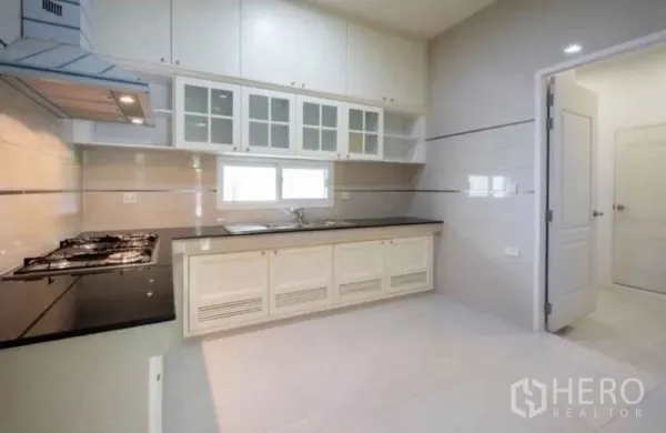 Detached House for rent or sale in Bang Phli, Samut Prakan - Bright Thai kitchen with white cabinetry, black granite countertop, gas hob and a window.
