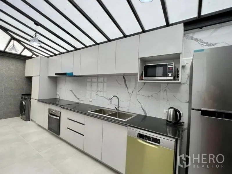 联排别墅 出租在Wang Thonglang, Bangkok - 采光天窗现代厨房，长台面、双水槽、烤箱、洗碗机、冰箱与微波炉。