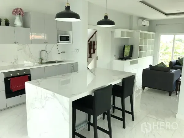 Detached House for rent or sale in Huai Khwang, Bangkok - Modern Western kitchen with marble island, pendant lights and an adjacent lounge.