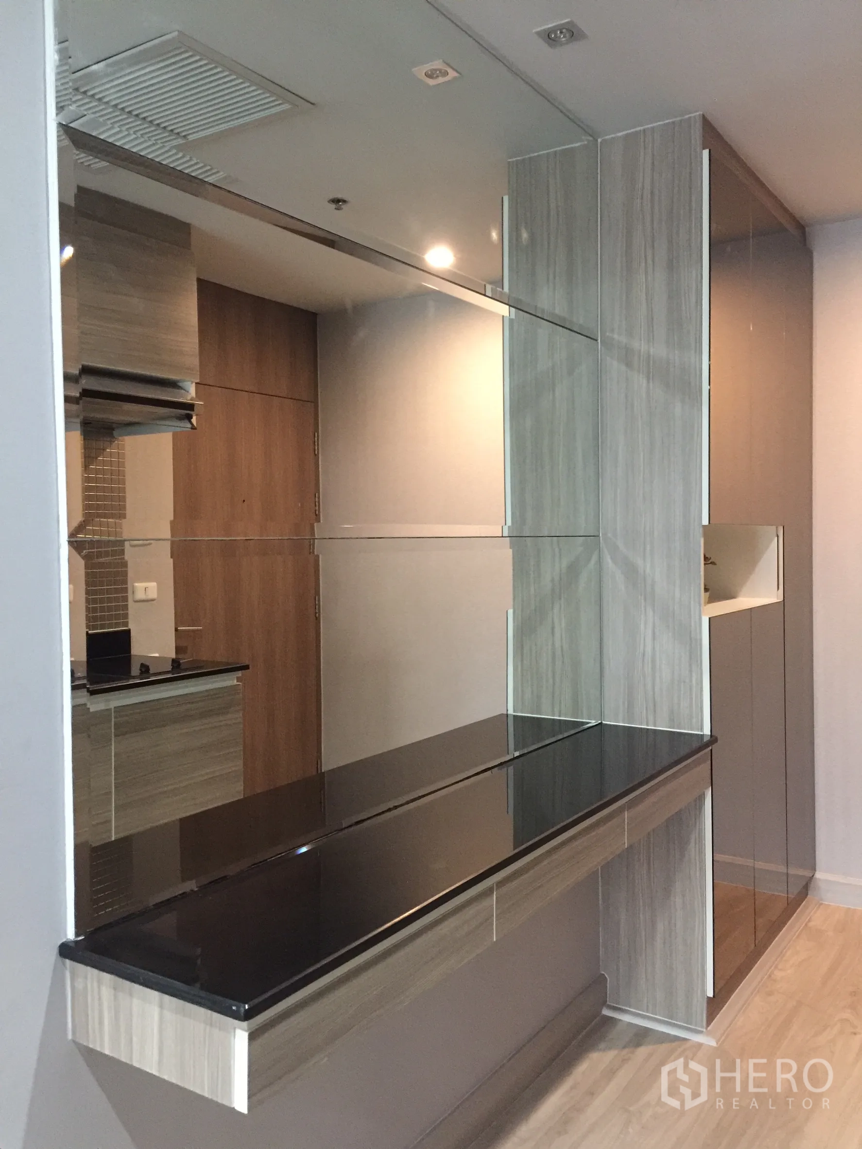 Condominium for rent or sale in Bangkok - Sleek black countertop and mirrored wall forming a breakfast bar area.