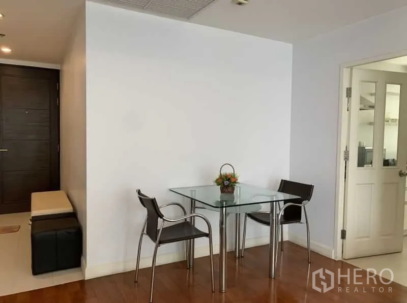 Condominium for rent in Khlong Toei, Bangkok - Cozy dining nook with a glass‑top table and two chairs beside the kitchen door.