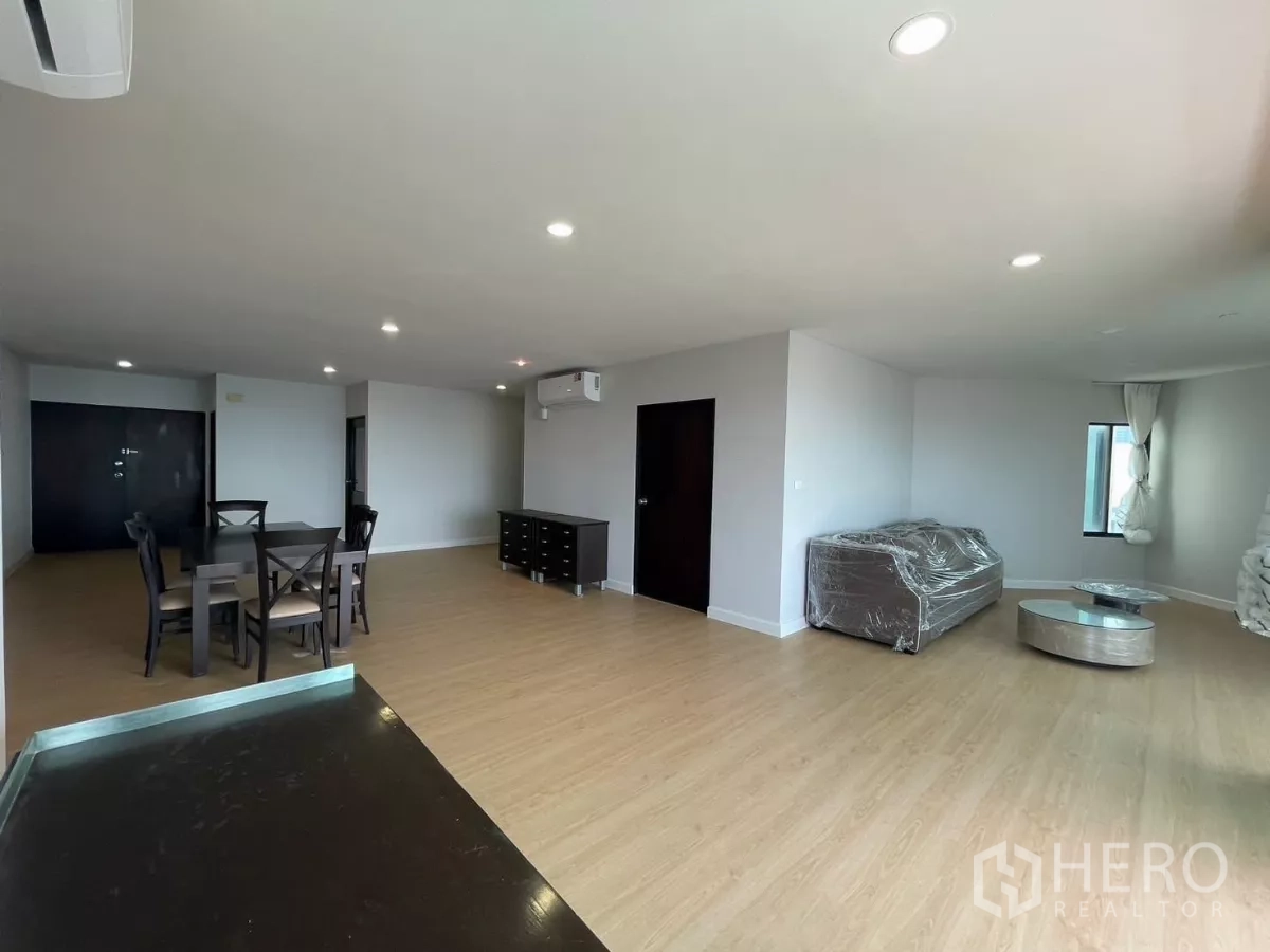 Condominium for rent in Sathon, Bangkok - Spacious open-plan living and dining area with wood floors and neutral walls.