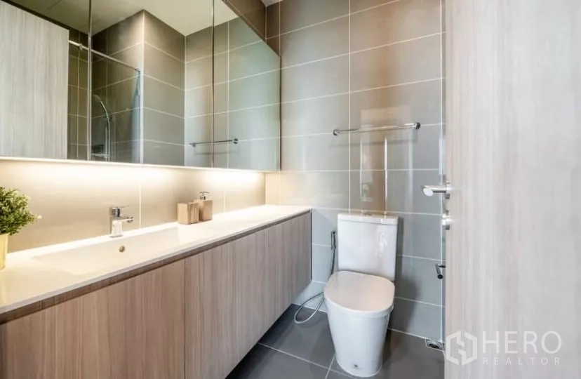 Condominium for rent in Chatuchak, Bangkok - Second bathroom with long vanity, large mirror and backlit lighting.