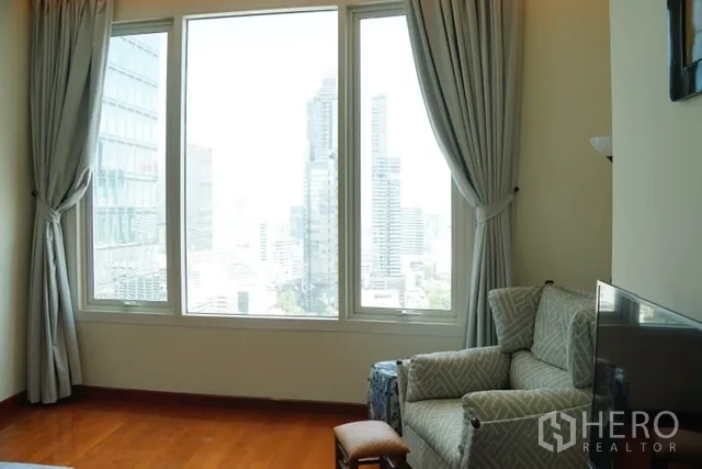 Condominium for rent in Bang Rak, Bangkok - Bright corner lounge with large window, drapes, and a sweeping skyline view of Bangkok’s business district.
