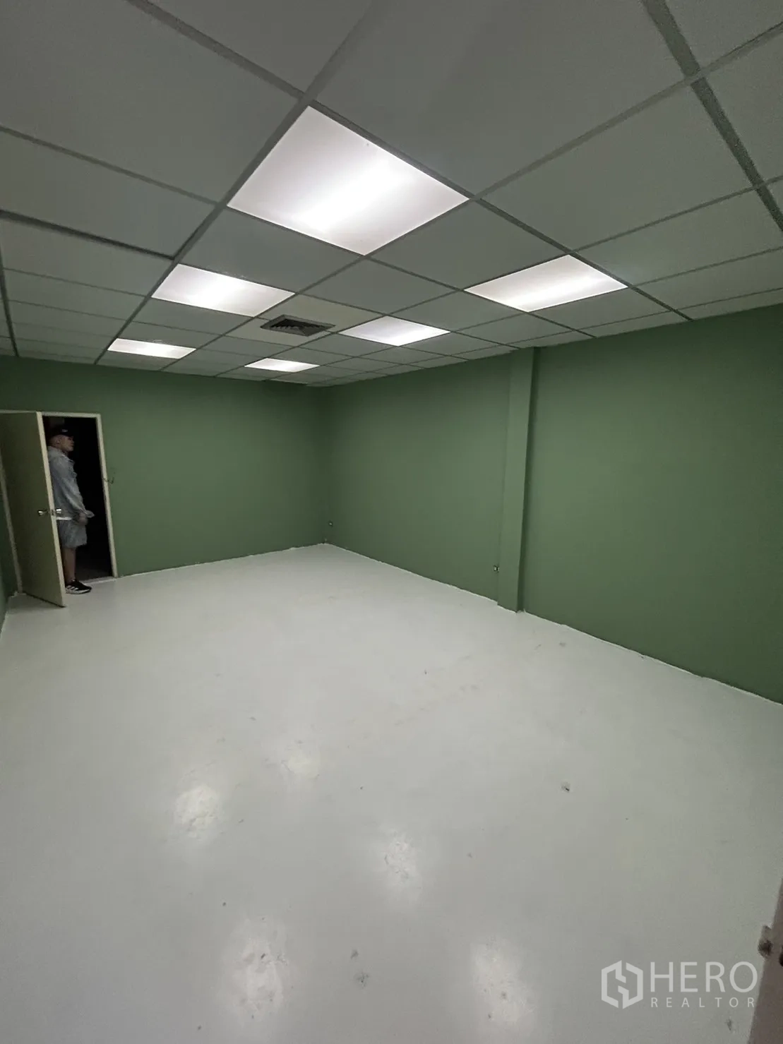 Shophouse for rent in Khlong Toei, Bangkok - Bright green-walled room with white floor and recessed panel lighting.