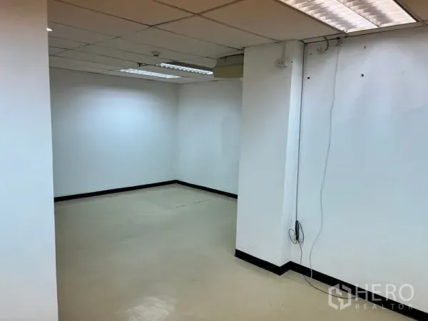Office Space for rent in Pathum Wan, Bangkok - Corner workspace with tiled floor, drop ceiling lighting and visible data and power points on the wall.