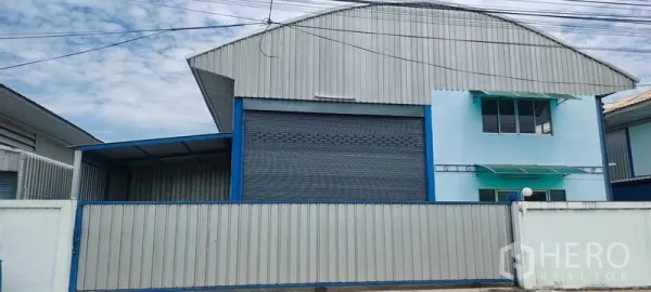 คลังสินค้า ให้เช่าในPathum Thani - มุมมองหน้ากำแพงโกดังแผ่นเมทัลชีท ประตูม้วนขนาดใหญ่ มีช่องหน้าต่างออฟฟิศและกันสาด ใต้หลังคาทรงโค้ง ในปทุมธานี