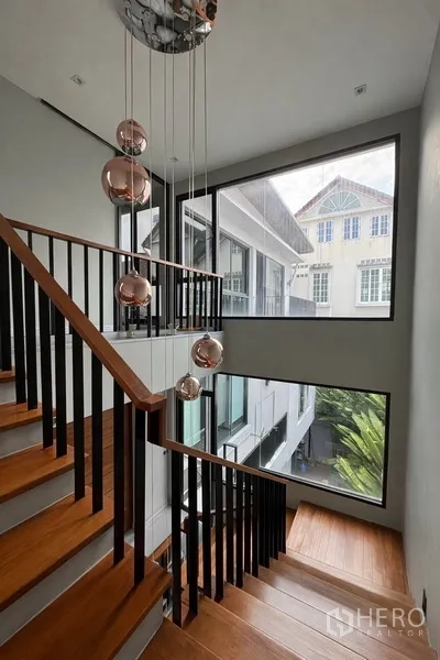 บ้านแฝด for rent in Watthana, Bangkok - บันไดไม้ราวเหล็กพร้อมหน้าต่างบานใหญ่และโคมแขวนดีไซน์