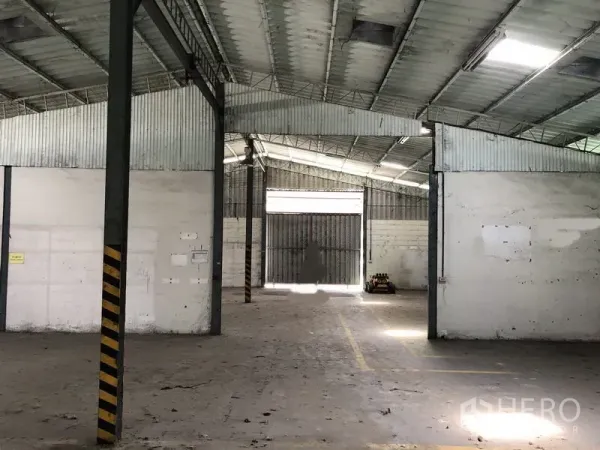货栈 出租在Khlong Luang, Pathum Thani - 仓内纵深通道，高挑屋顶，尽头为大型钢制大门。