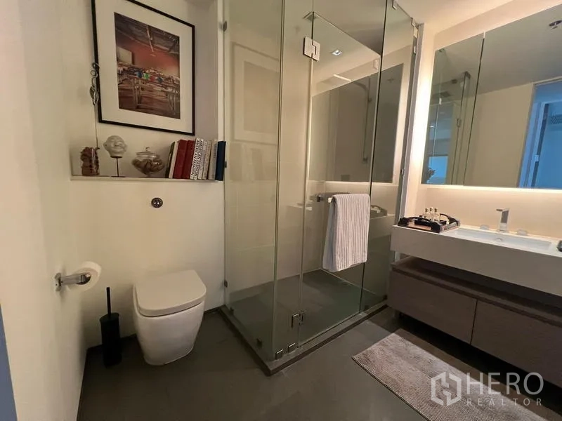 Condominium for sale in Khlong San, Bangkok - Modern bathroom featuring glass shower, floating vanity, and wall mirror.