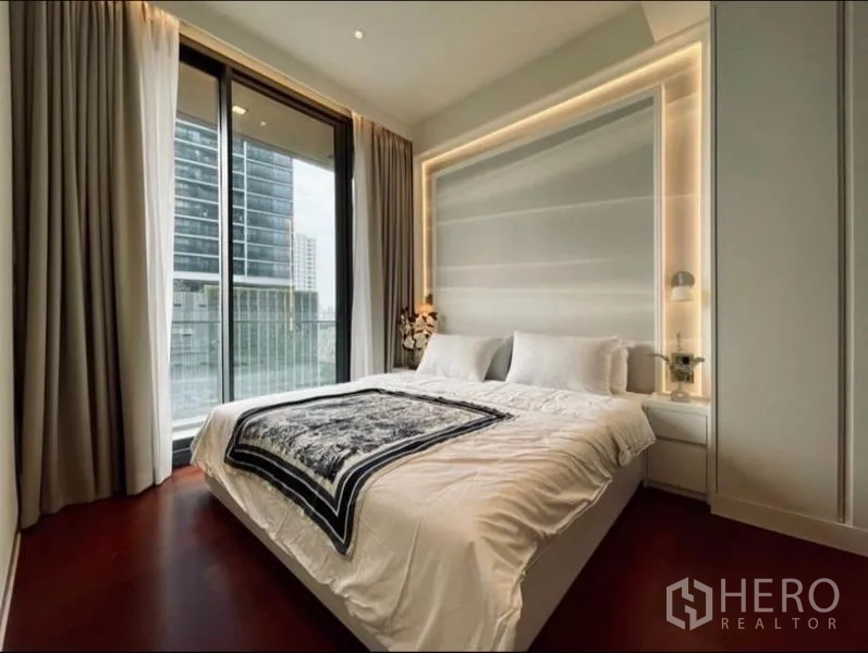 公寓 出租在Watthana, Bangkok - 卧室配大床与氛围灯，落地窗通往阳台与城市天际线