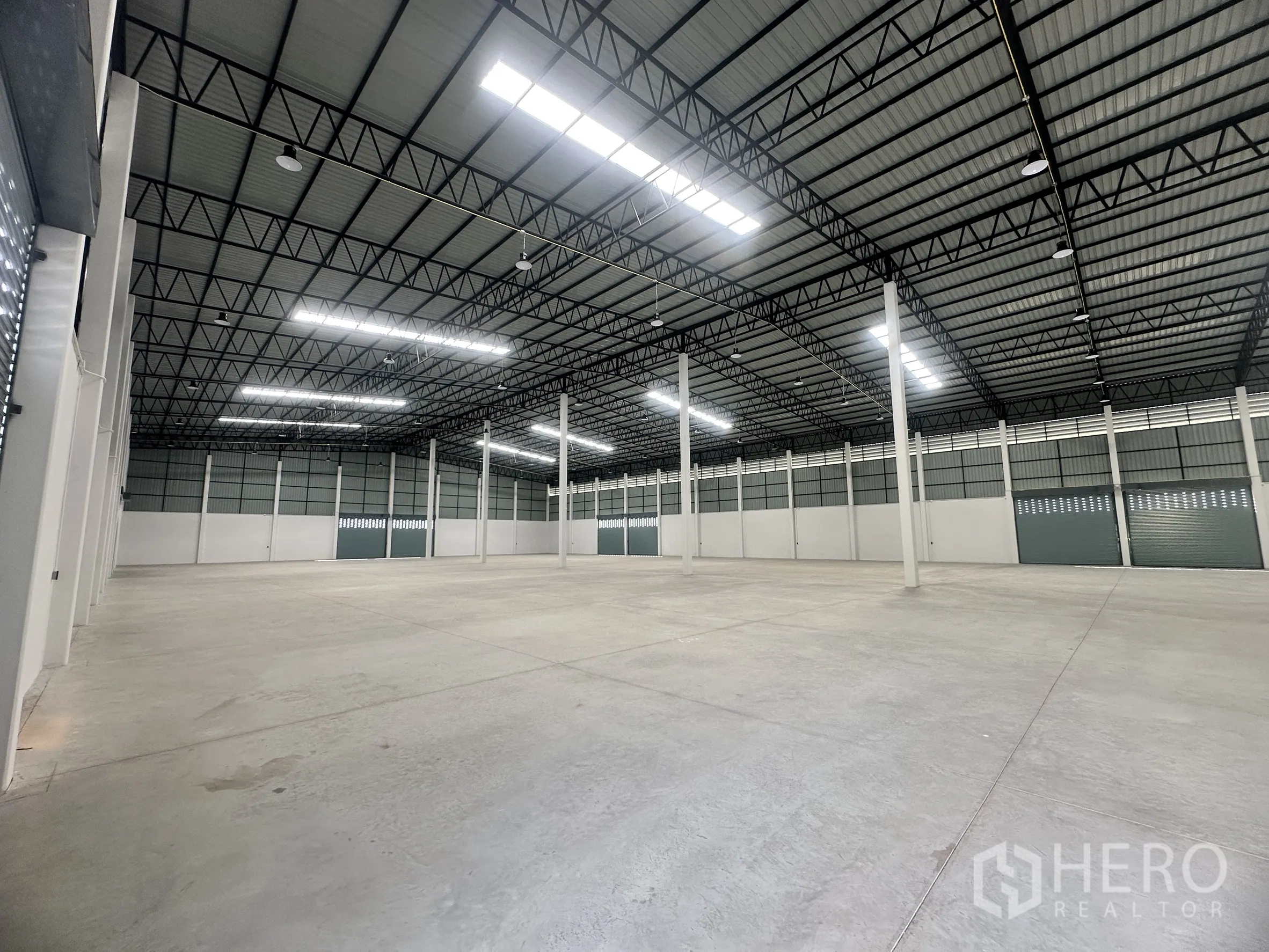 工厂 for rent or sale in Bang Len, Nakhon Pathom - 宽敞仓库内部，高钢结构屋顶、明亮灯光与光滑混凝土地面。