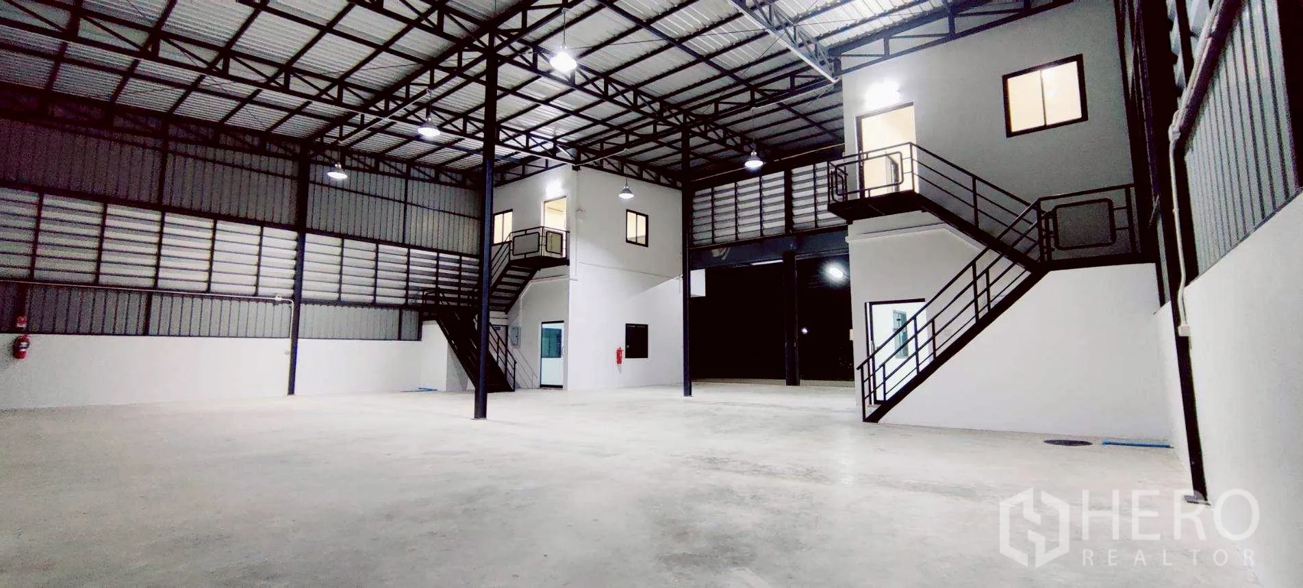 Warehouse for rent in Lam Luk Ka, Pathum Thani - High‑ceiling warehouse interior with steel trusses and mezzanine offices.