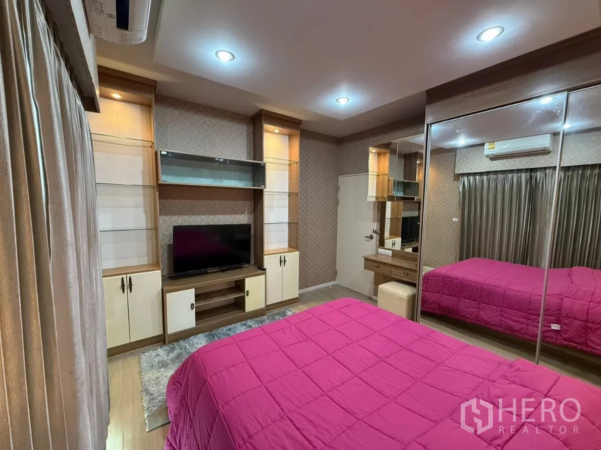Townhouse for rent in Suan Luang, Bangkok - Third bedroom view toward TV wall with glass shelving and cabinets.