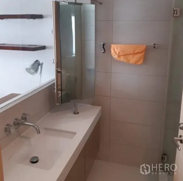 Condominium for rent in Khlong Toei, Bangkok - Contemporary bathroom with long vanity, wall-mounted faucet and tiled shower area.