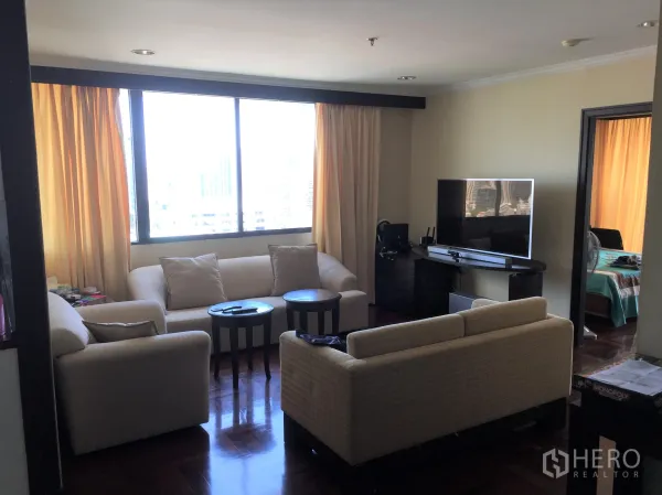 公寓 出租或出售在Khlong Toei, Bangkok - 客厅配米色沙发、电视柜和大窗，可观赏城市天际线。