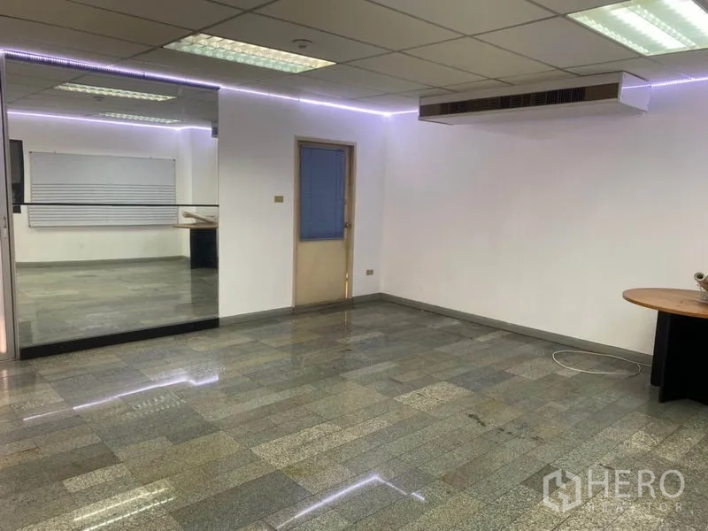 Office Space for rent in Khlong Toei, Bangkok - Spacious open-plan office with ducted AC, reflective tile floors and a glass wall divider.