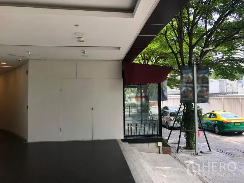 Retail Space for rent in Watthana, Bangkok - Covered entrance with ramp beside a glass storefront and leafy street in Watthana.