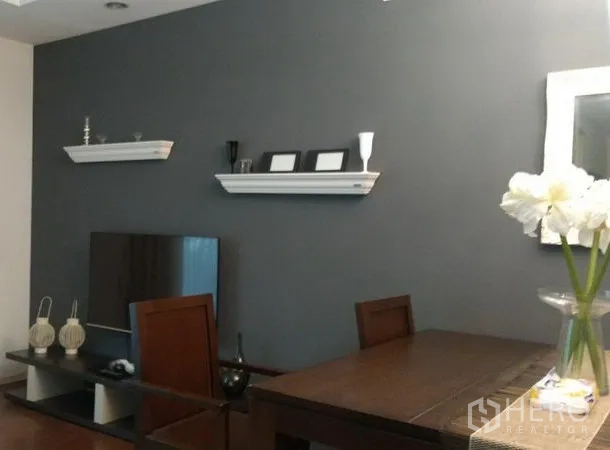 公寓 出租在Khlong Toei, Bangkok - 餐桌与电视柜相邻，灰色主墙搭配悬浮层板装饰。