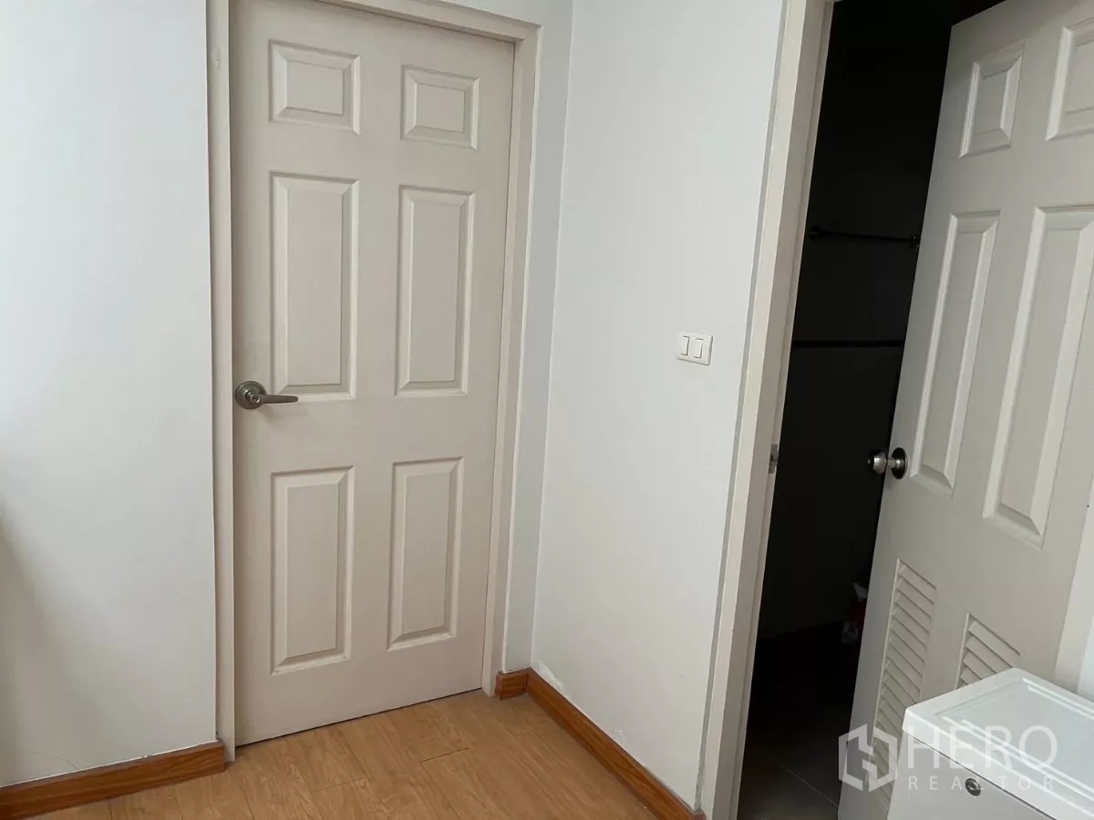Townhouse for rent in Bang Kho Laem, Bangkok - Upper hallway with two cream doors and wood-look flooring.