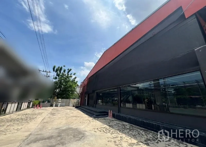 Showroom for rent in Mueang Samut Prakan, Samut Prakan - Front driveway and entrance with wide glass storefront and red metal roof