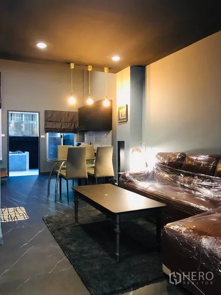 Townhouse for rent in Bang Kapi, Bangkok - Open-plan living and dining area with pendant lights, leather sofa and coffee table.