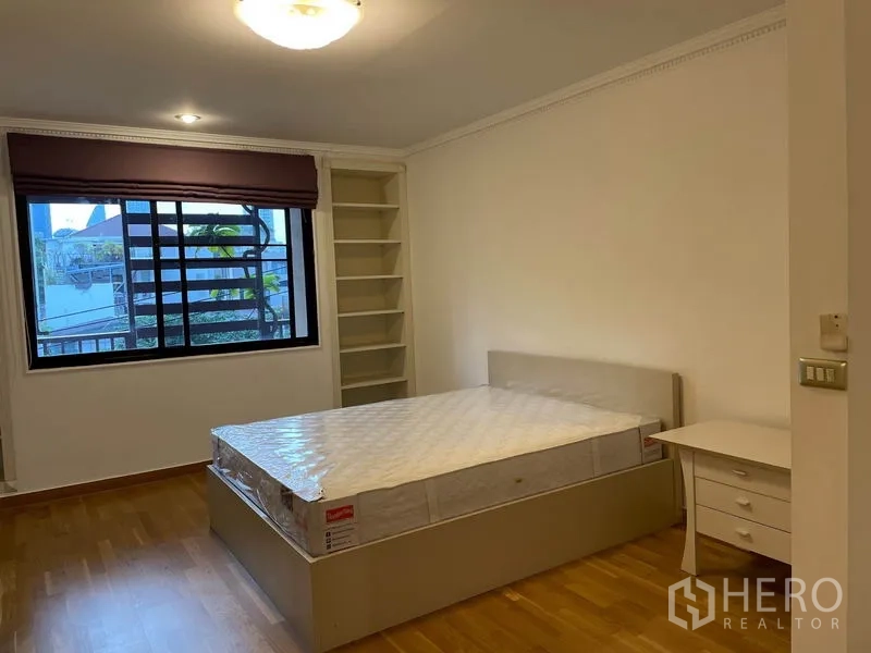 Condominium for rent in Watthana, Bangkok - Guest bedroom with built-in shelves, window views, wood floors and a queen bed.