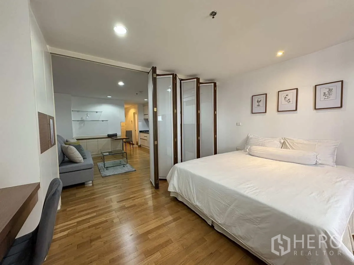 Condominium for rent in Khlong Toei, Bangkok - Bedroom view toward living area through folding doors over hardwood flooring.