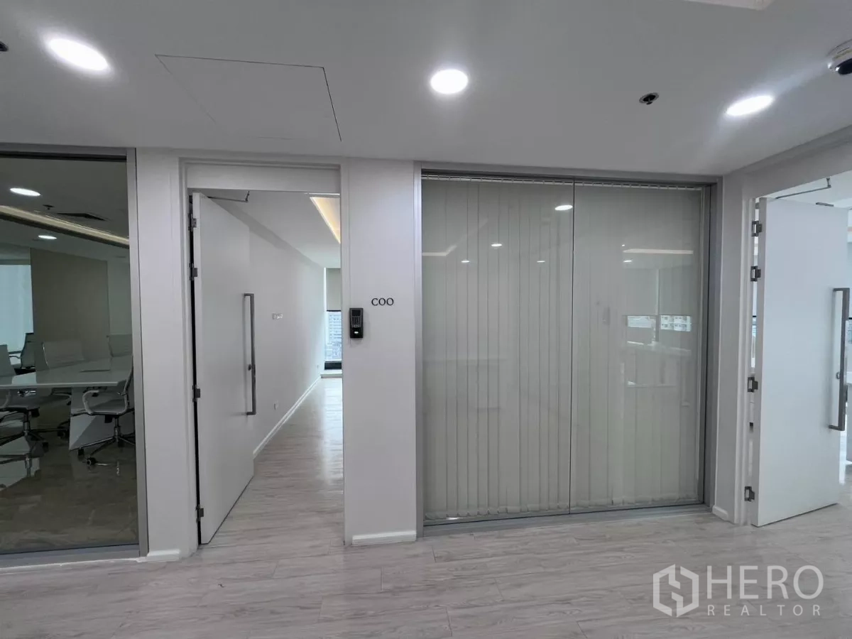 办公空间 出租在Din Daeng, Bangkok - 走廊设行政办公室入口与带百叶的玻璃隔断，照明明亮现代。