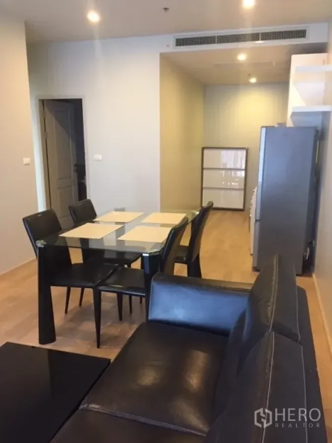 Condominium for rent in Bangkok - View from lounge toward dining and kitchen showing a four-seat glass table and ceiling-concealed air-conditioning.