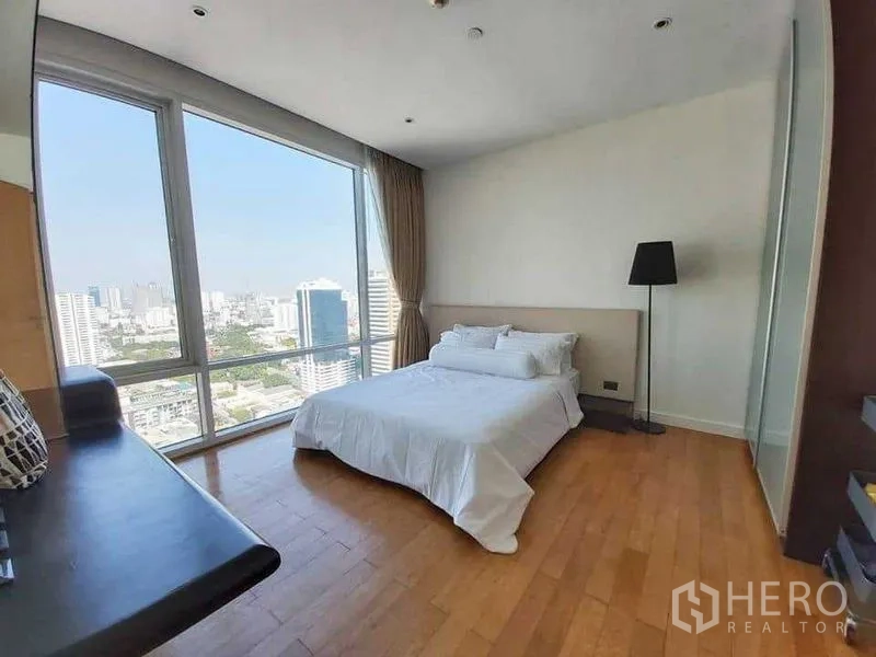 Condominium for rent in Watthana, Bangkok - Sunny bedroom with wood floors, large window, and panoramic skyline view.