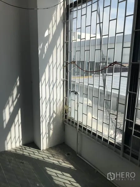 Office Space for rent in Khlong Toei, Bangkok - Sunlit corner with tall window and security bars facing nearby buildings.