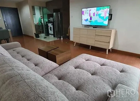 คอนโด ให้เช่าในHuai Khwang, Bangkok - มุมมองจากโซฟาไปยังทีวีบนตู้ไม้ พร้อมครัวเปิด ตู้เย็น และเครื่องซักผ้า