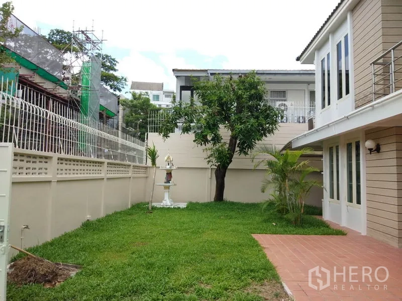 独立式住宅 出租在Watthana, Bangkok - 私家庭院草坪配树木与围墙，旁侧为红砖露台