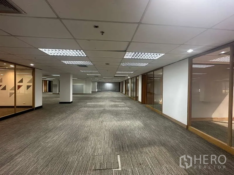 Office Space for rent in Khlong Toei, Bangkok - Long corridor-style open office with carpet flooring and glass partitions.