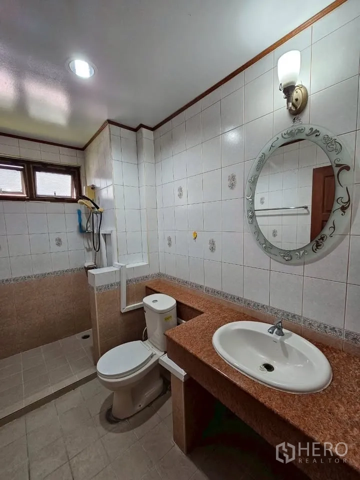带办公室的家 for rent in Wang Thonglang, Bangkok - 白瓷砖浴室，橙色石材台面、坐便与圆镜。